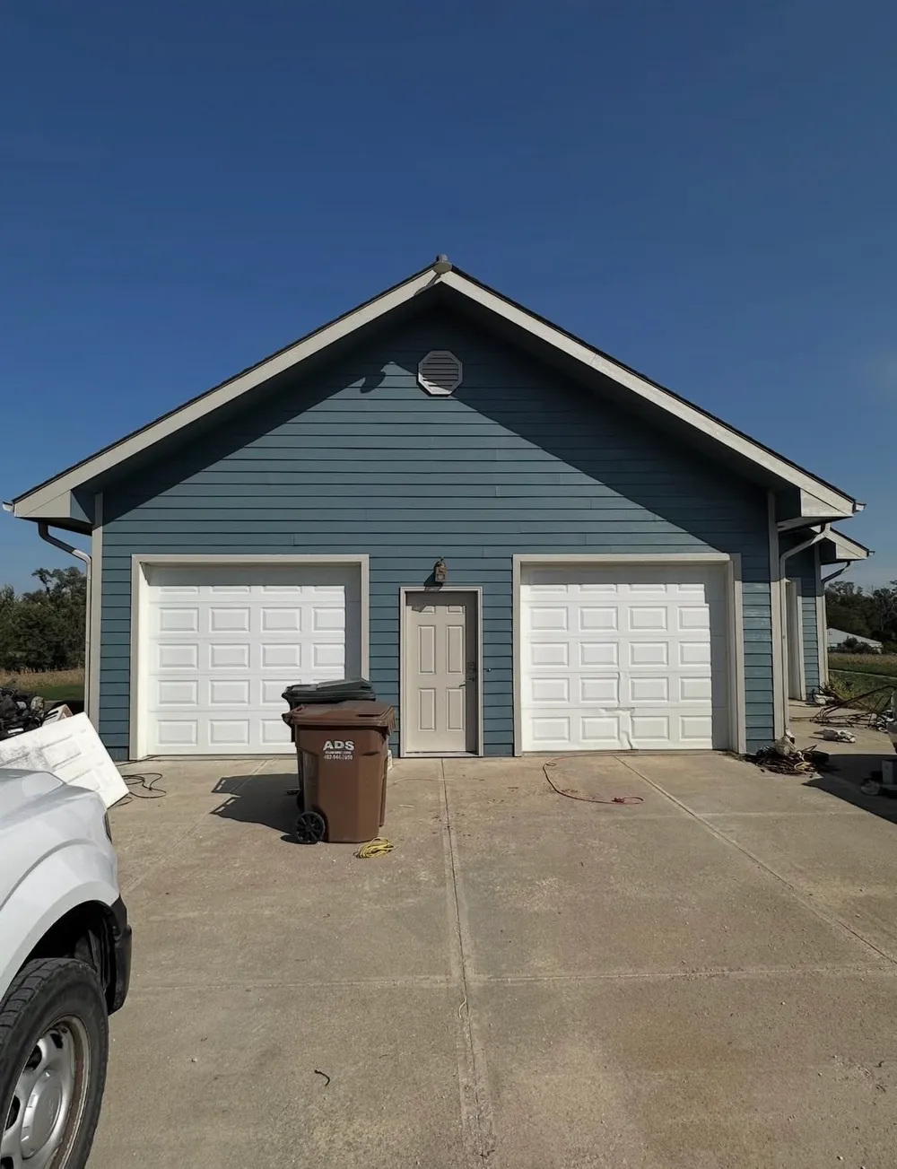 After — detached garage freshly painted deep blue with white trim